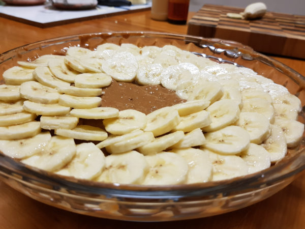 Bananas arranged on top of caramel layer of banoffee pie.